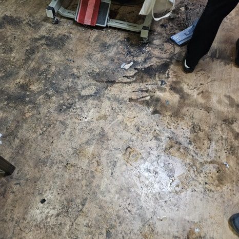 검은 오염을 한 차례 닦아낸 합판 표면. 흰 가루 형태의 소독·중화제 잔여물과 옅은 얼룩 자국이 남아 있다